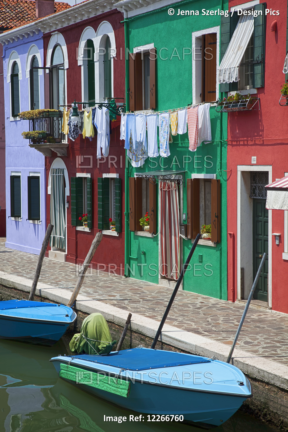 Blue Boats Sit In Front Of A Row Of Colourful Houses; Burano, Venice, Italy