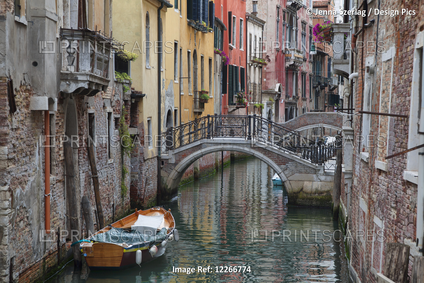 A Small Canal With A Boat And Bridge; Venice, Italy