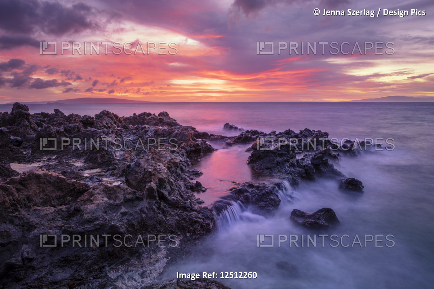Dramatic sunset over the ocean with waterfalls along the rugged coastline; ...